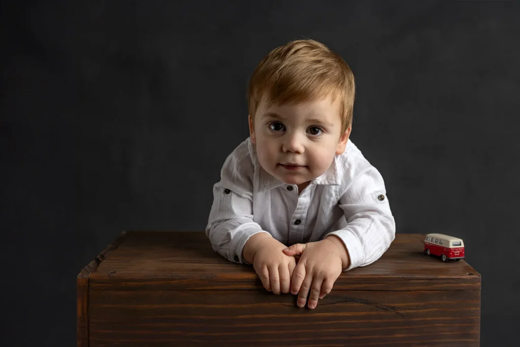 Baby boy leaning on a wooden box during a professional studio portrait session