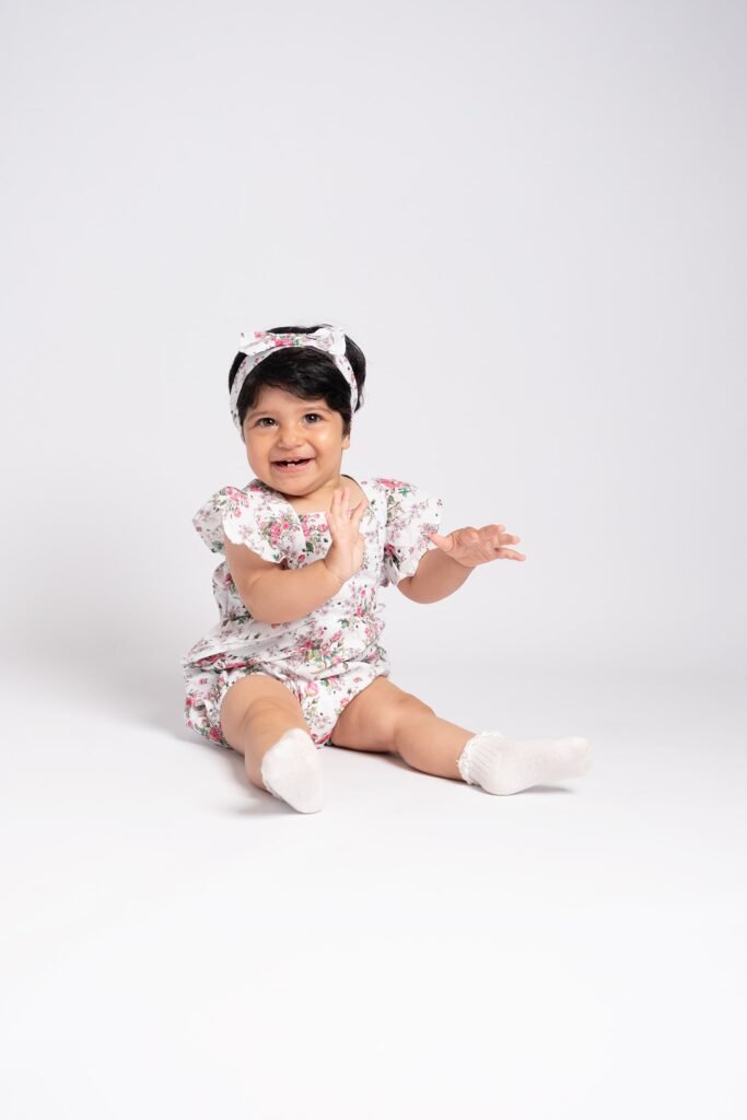Baby girl sitting independently during a clean white studio sitter portrait session