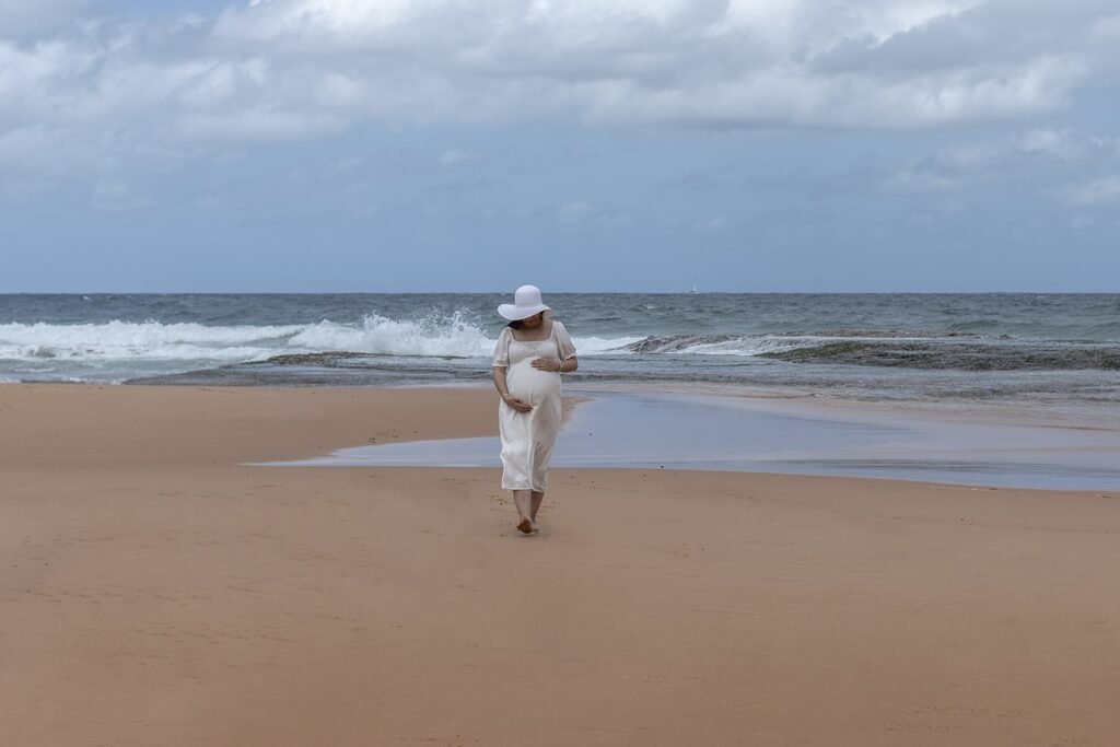 Pregnant woman walking along a Sydney beach during an outdoor maternity session