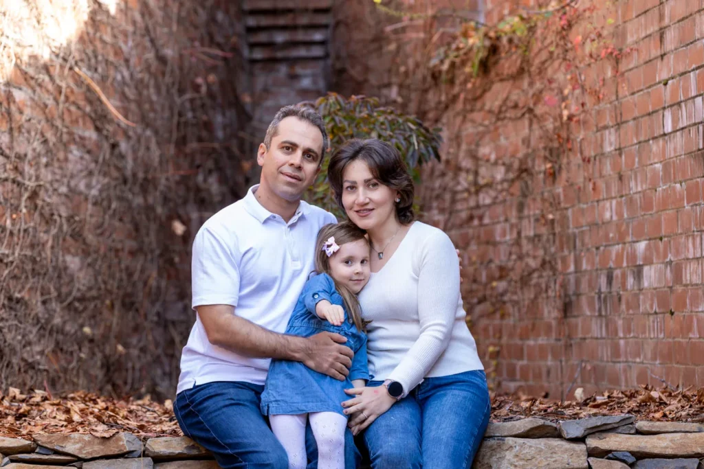 Parents sitting with their young child during an outdoor family portrait session