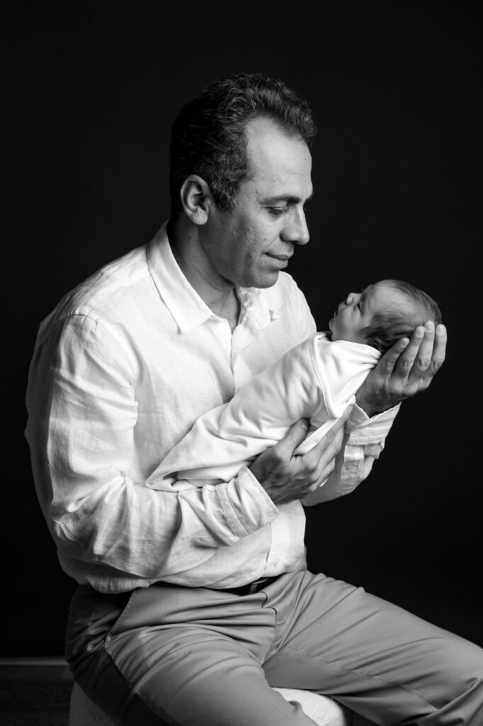 Father holding his newborn baby during a black and white studio portrait session