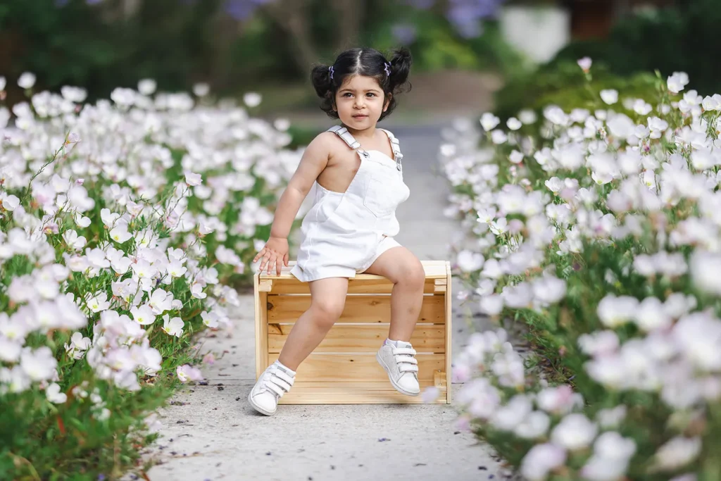 Young girl standing among white flowers during an outdoor children’s portrait session