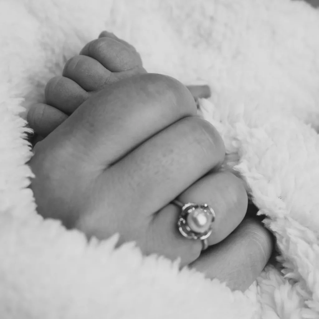 Love in the Details, Newborn baby feet photographed with parents’ wedding rings in black and white