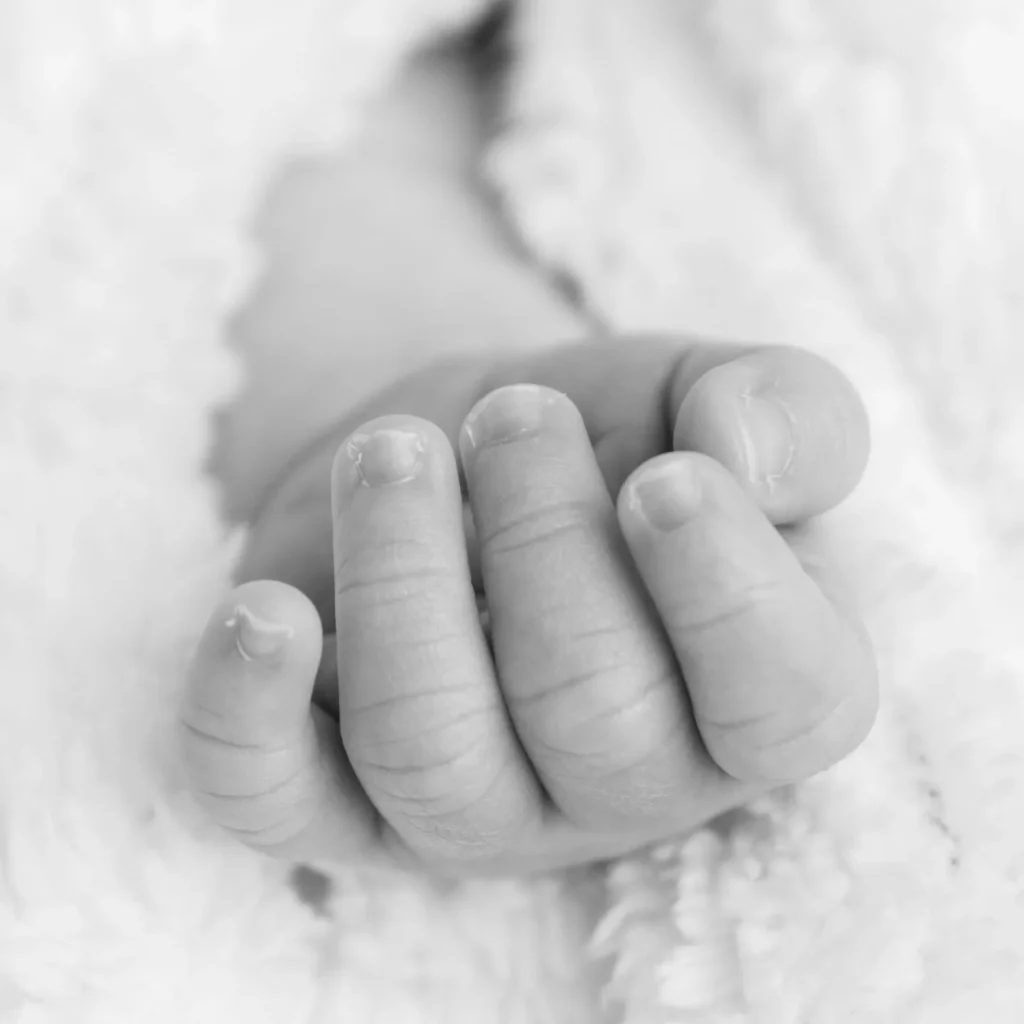Close-up black and white photograph of a newborn baby’s hand