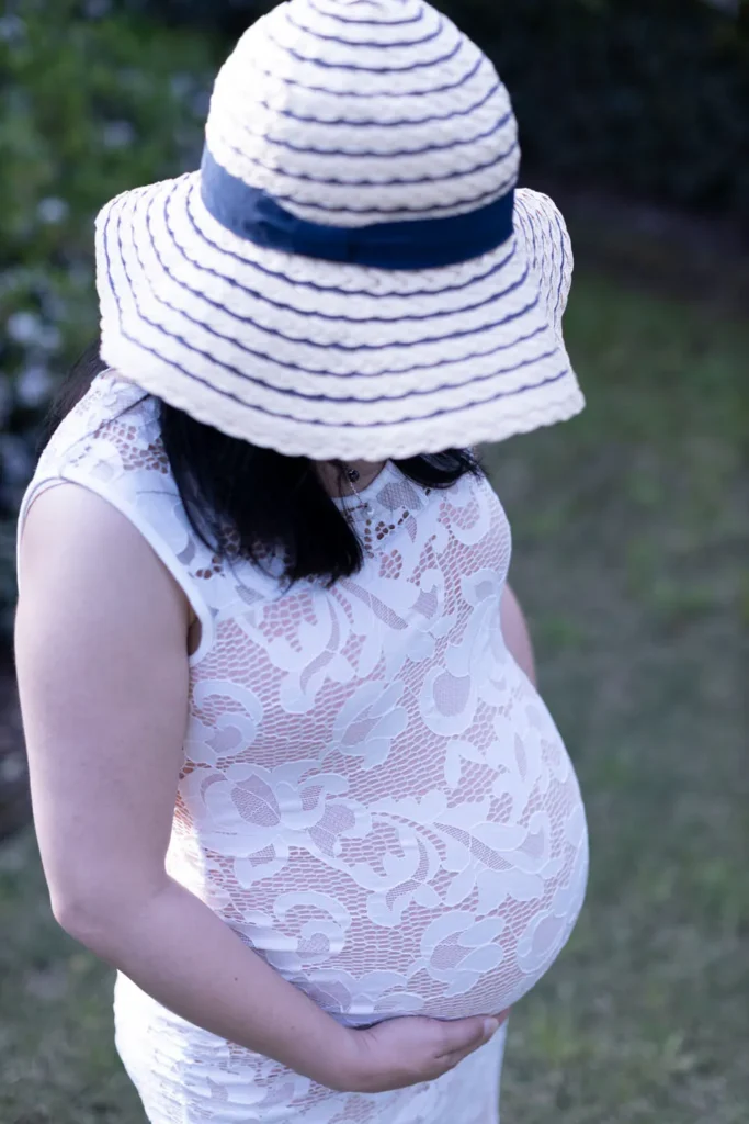 Pregnant woman photographed outdoors wearing a sun hat during a maternity session